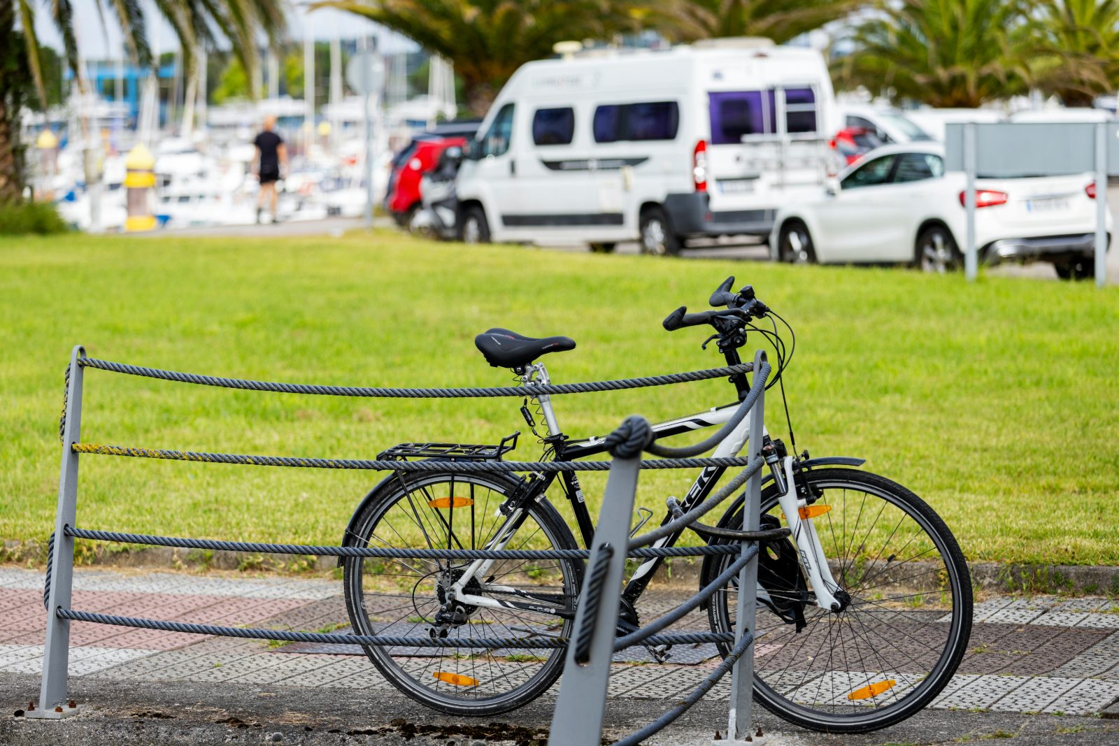 Bicicleta asegurada en un punto de parqueo cerca de una zona de vehículos